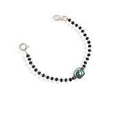 A sterling silver bracelet for kids featuring a green heart charm and black and white beads.